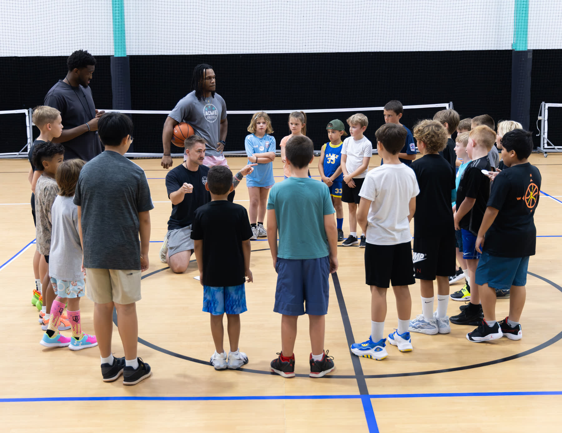 ACME coaches huddled with young athletes on the indoor court